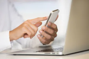 Woman using cell phone by laptop - Mobile App STD Results