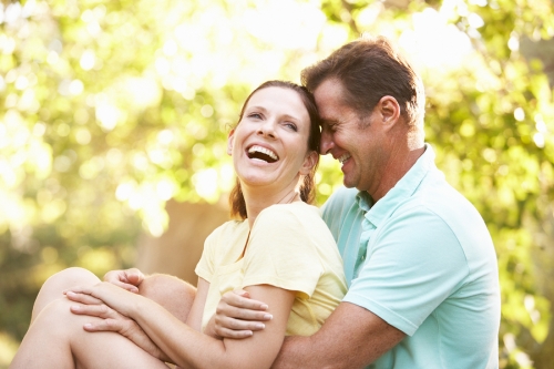 Young Couple In Walking Clothes Resting On Tree In Park