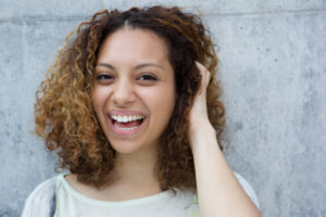 Close up portrait of a cheerful young woman laughing with hand in hair