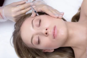 Cosmetologist making injection into crow's feet.