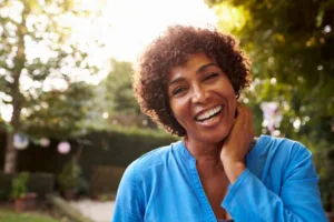 A woman standing outside confidently smiling.