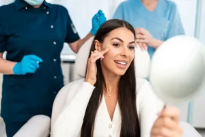A woman looking into a mirror after receiving a dermal filler treatment.
