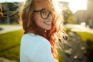 A woman smiling confidently while standing outside.