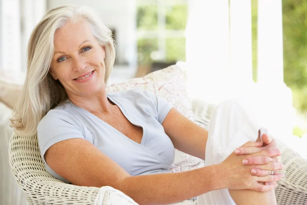 A confident woman sitting in her backyard after recovering from menopause discomfort.