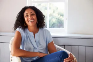 A confident woman smiling while sitting in her living room.