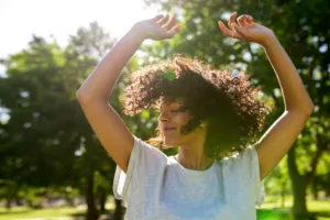 A confident woman with her arms in the air while walking outside.