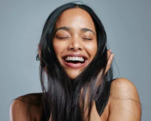 A woman holding her hair and smiling confidently.