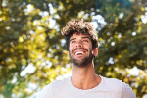 A confident man smiling while running outside.