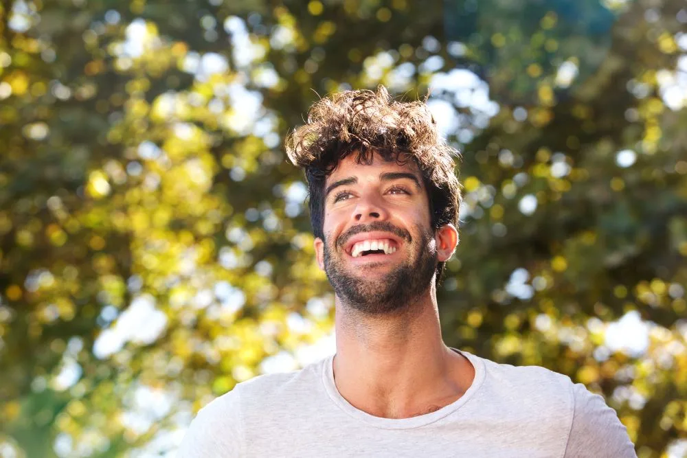 A confident man smiling while running outside.