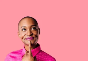A woman smiling with her finger towards her chin in curiosity.