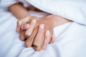 Close up of a couple's hands while in bed.