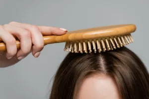 Cropped view of young woman brushing shiny and healthy hair.