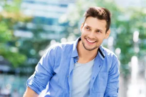 Smiling man sitting outside.