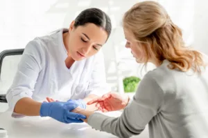 Dermatologist in white coat examining skin of patient in clinic