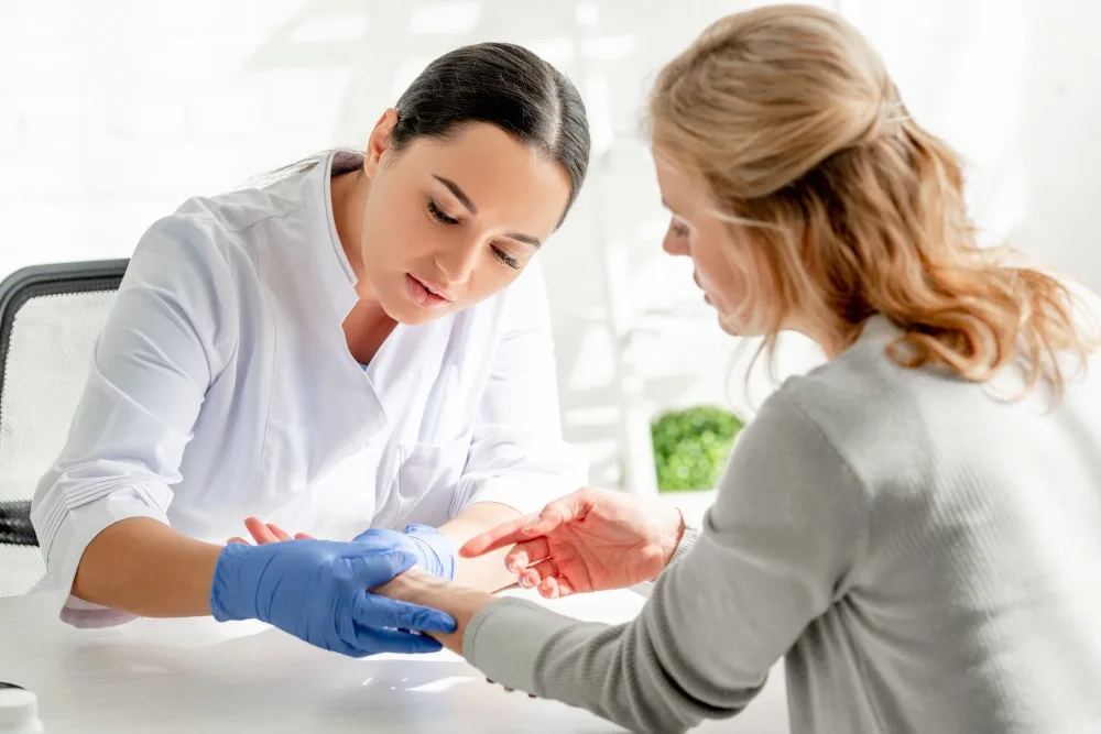 Dermatologist in white coat examining skin of patient in clinic